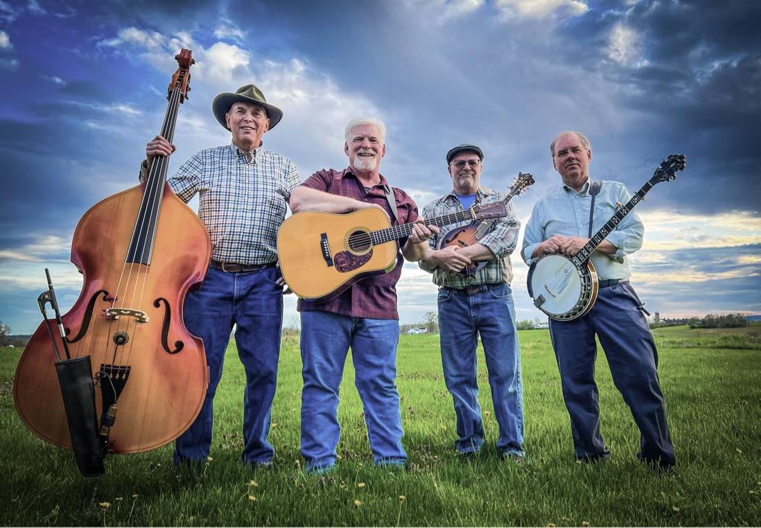 The High Peaks Bluegrass Band musicians pose with their instruments - four men hold a bass, guitar, mandolin, and banjo.